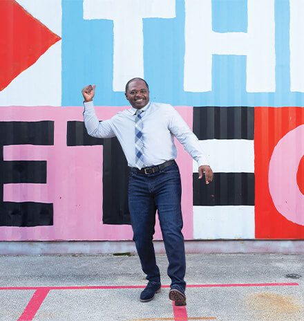 arnett morris standing in front of the off the street club painted sign