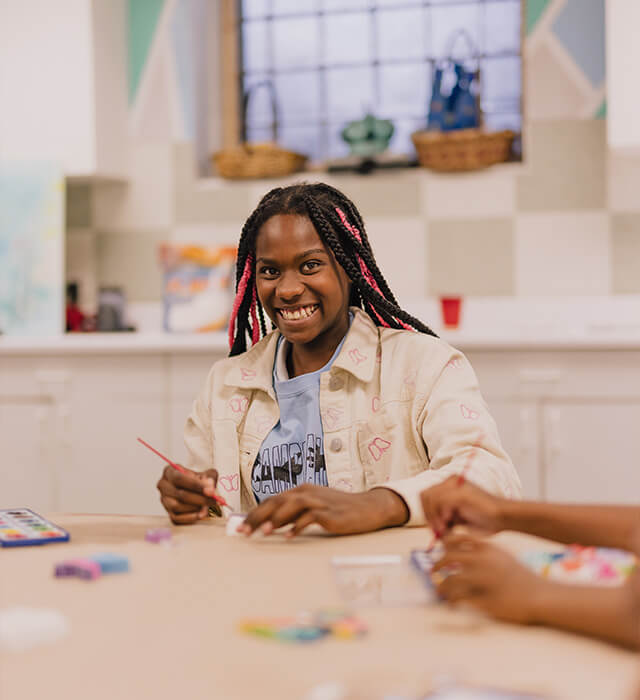 girl smiling and painting at a table