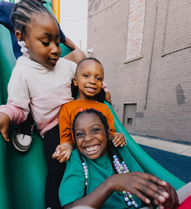 three kids on the playground slide