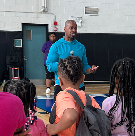 man talking to kids in a gym